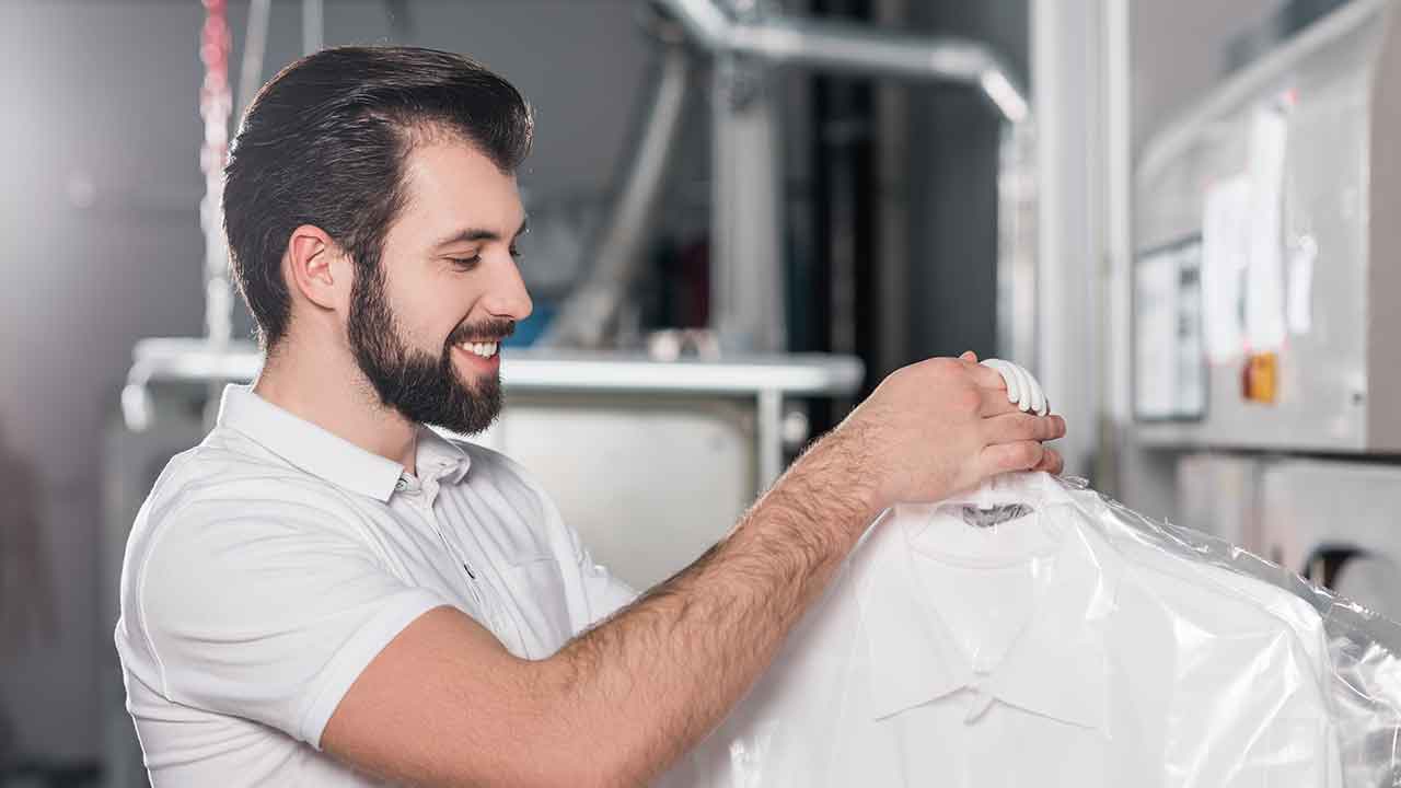 A man is putting a shirt on a drying rack.